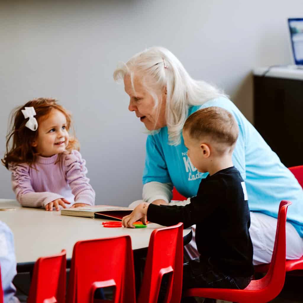 A woman reading a story to children at North Way Kids