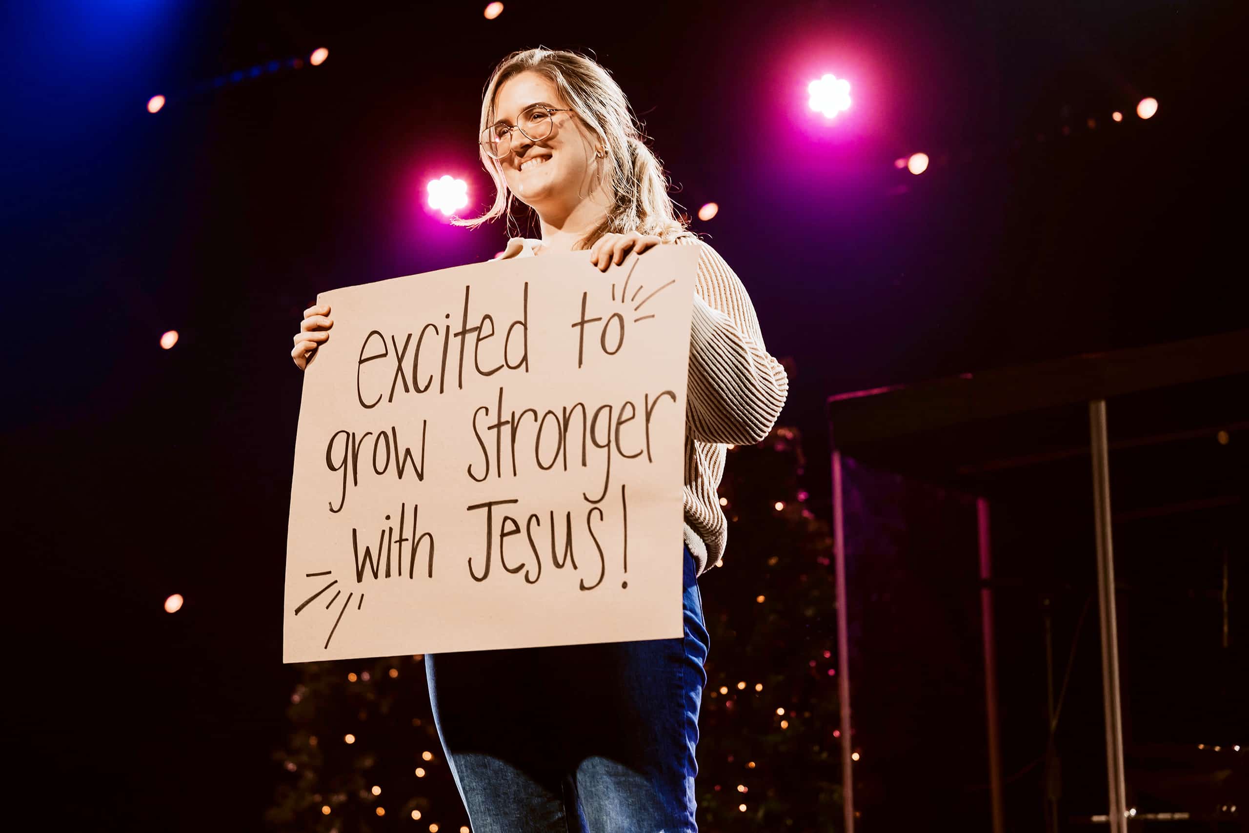A woman on stage sharing her story and inviting others to know Jesus and get connected at with one of our Churches in Pittsburgh PA.