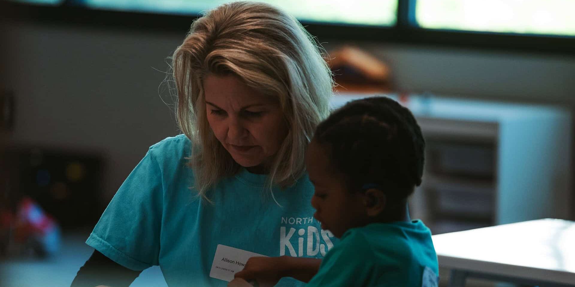 A Kids Ministry volunteer coloring with a kid.