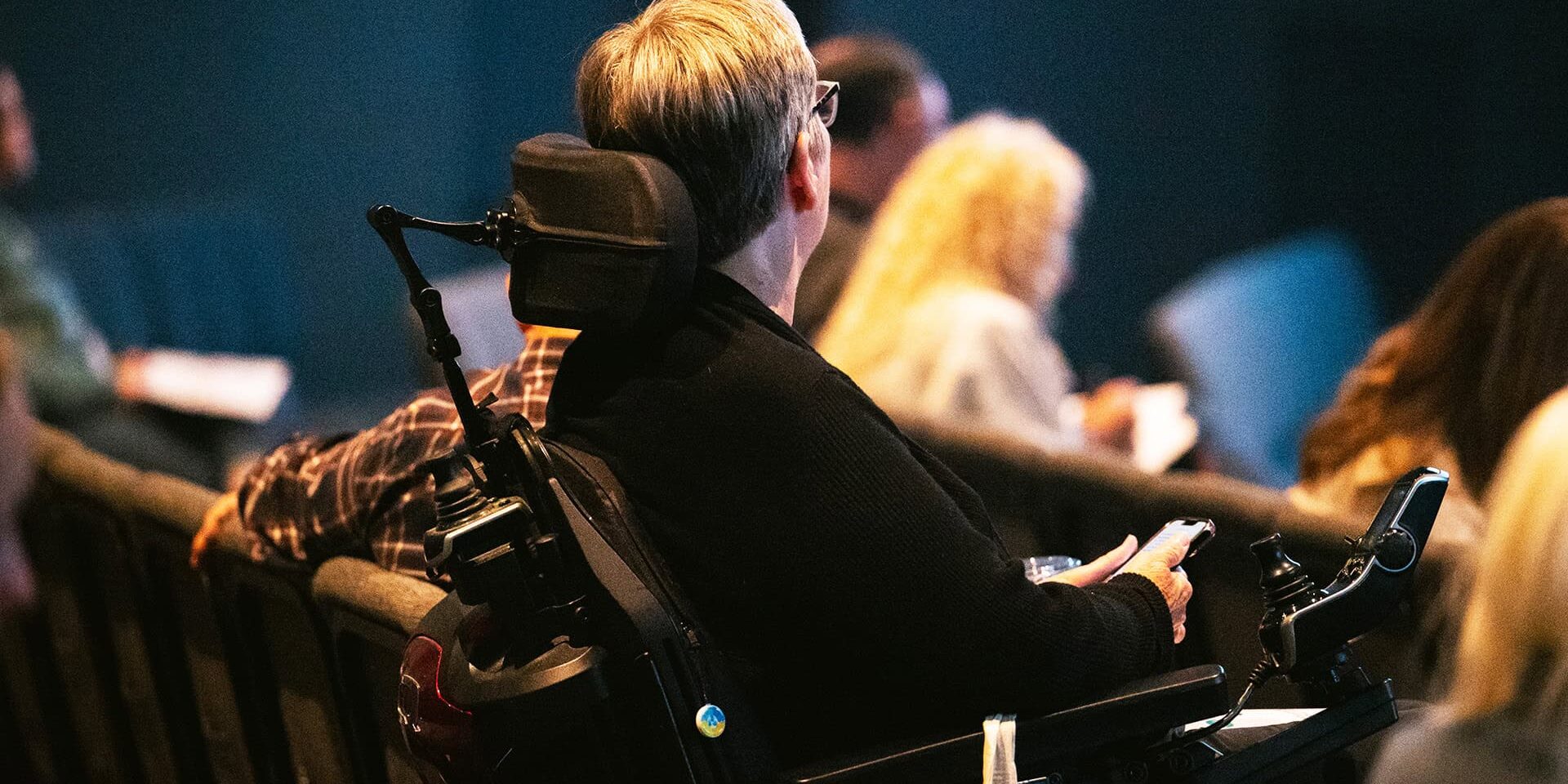 A man in a wheelchair listening to a speaker at the Faith and Disability Conference at North Way Sewickley Valley