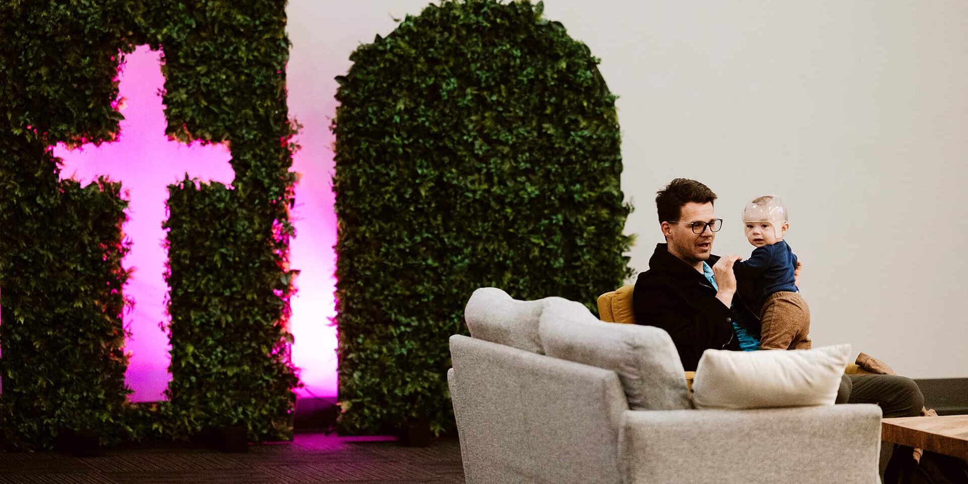 A father holding his infant in the lobby at North Way Sewickley Valley, a non-denominational church in Sewickley PA